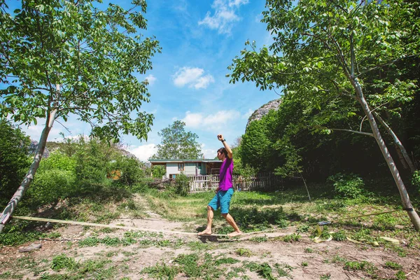 Man walking on a slack line outdoor in a park, summer vacation hobby.