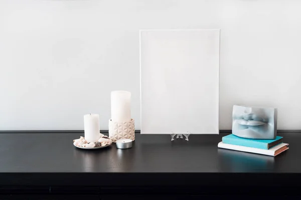 部屋のインテリアデザイン アーティストのモックアップのための空白の白いキャンバス 乾いた花の花束と唇の形の花瓶 キャンドル 黒いテーブルと白い壁に白い本 ミニマリズム — ストック写真