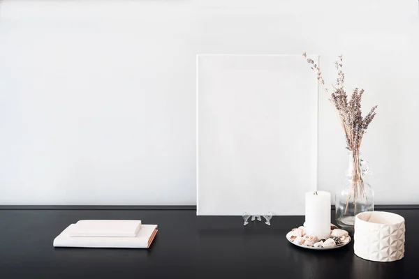 白布画布为艺术家的模型 玻璃瓶瓶与干花束 白书黑桌和白墙 简约主义风格 免版税图库照片