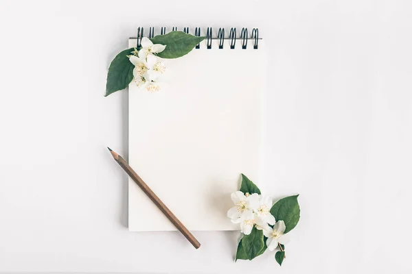 Notepad with pencil and flowers.