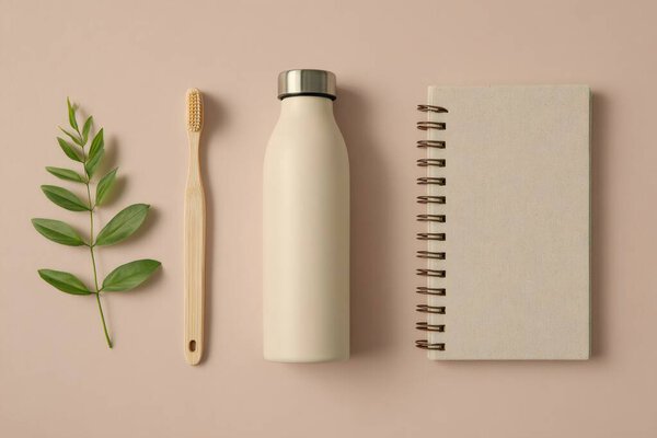 Sustainable lifestyle essentials scattered on minimalist surface, highlighting zero-waste products including reusable water bottle, bamboo toothbrush, recycled notebook
