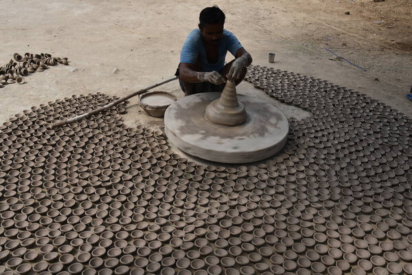Bikaner, Rajasthan / India, October, 19,2019: A potter and a group of lamps made in front of earthen lamps on chalk in Gangahar Bikaner