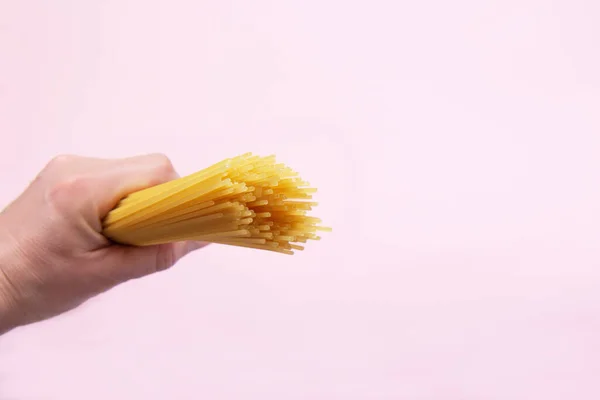 Mão segura espaguete cru — Fotografia de Stock