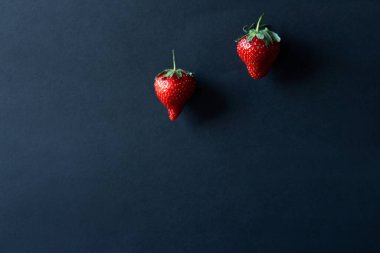 Siyah arka planda iki çilek.