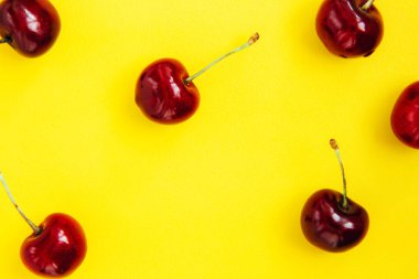Sarı arka planda parlak kırmızı kiraz. Kiraz deseni. Kirazlar kapanıyor. Yaz yassı böğürtlen arka planı. Üst görünüm