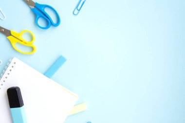 Okul kırtasiyesi ve malzemeler mavi arka planda, altyazı için yer var. Okula geri dönmek, evde yaratıcı çalışma alanı. Rengarenk kırtasiye seti. Düz yatıyordu