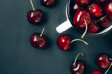 Koyu arkaplanda demir bir fincanda kırmızı kirazlar