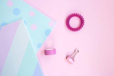 İki parlak eskiz kitabı, seloteyp, pembe ataç ve pembe arka planda saç teli. Pembe arka planda kırtasiye malzemesi, mesaj için yer var. Okula, yaratıcı çalışma alanına. Düz yatıyordu