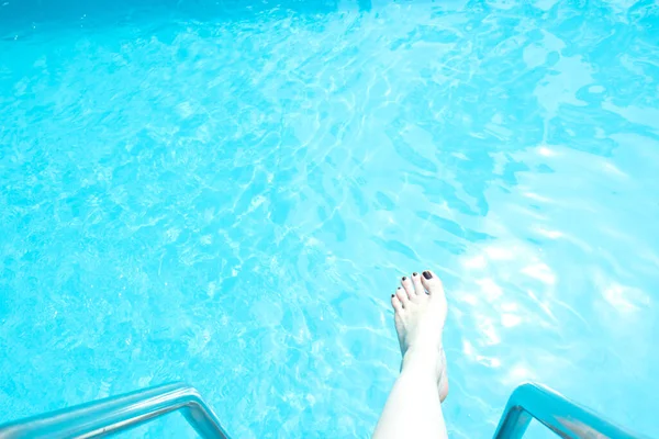 Pierna femenina en la piscina. Vacaciones de verano — Foto de Stock