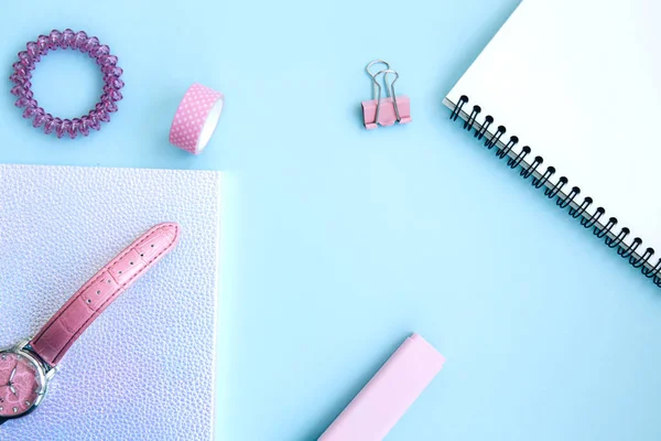 Pembe kızlar için. Neon defter, selobant, saat, klipsler, silgi, pembe arka planda açık not defteri ve saç teli. Mesaj için yer var. Okula hazırlanıyorum. Yaratıcı çalışma alanı. Düz yatıyordu