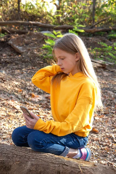 Krásné teen blondýny dívka v jasně oranžové mikiny v podzimním parku — Stock fotografie