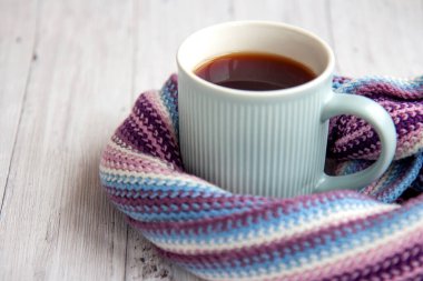 Mavi fincan sıcak çay sıcak çizgili çok renkli bir eşarba sarılır. Kopyalama alanı olan sonbahar arkaplanı