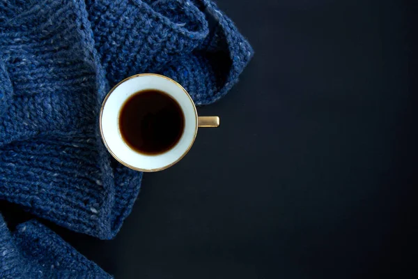 Blauer Strickpullover, Goldbecher mit Kaffee auf dunkelschwarzem Hintergrund — Stockfoto