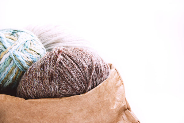 Яйца пряжи в обнаженном цвете в ремесленной сумке на ярком фоне. На белом фоне с копировальным пространством. Трикотаж как концепция женского хобби