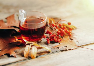 Sonbahar yapraklı ve çilekli bir fincan sıcak çay.
