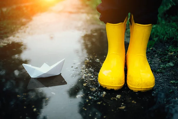 A child plays with a paper boat