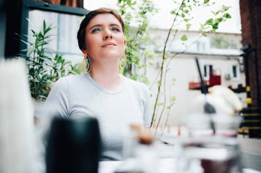 Genç bir kadın bir kafede oturuyor.