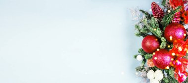 Mavi arka planda kırmızı süslemeleri olan Noel ağacı dalları