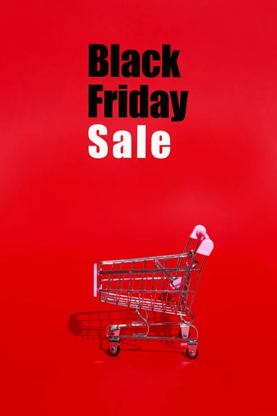 Shopping cart for purchases on red background with text. Black Friday pattern concept