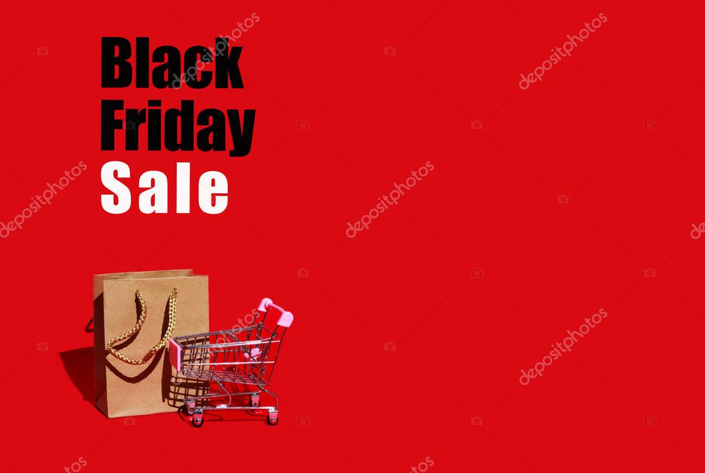 Shopping cart and paper bag for purchases on red background with space for text. Black Friday concept