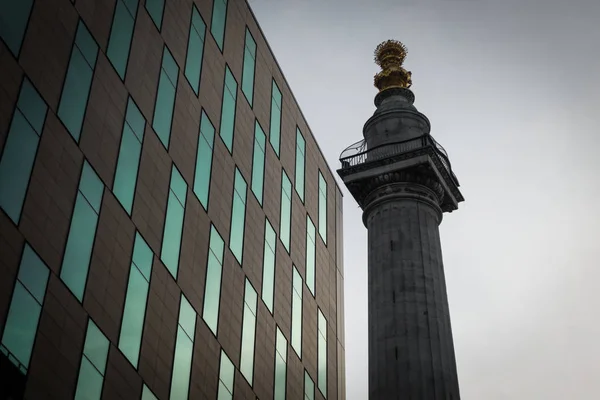 Il monumento al grande incendio in contrasto con un edificio moderno . — Foto Stock