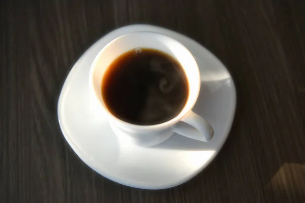 Flat lay of black hot coffee with sunlight on table