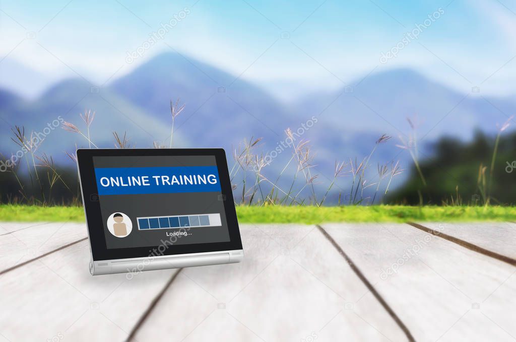 Computer tablet with online learning loading screen with grass on plank and mountain landscape view background, smart technology concept and online learning idea