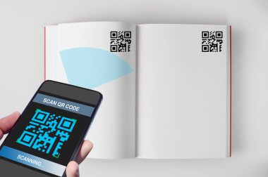 Tarama Qr kodu açık kitap ekranda beyaz arka plan, akıllı teknoloji kavramı ve Qr kodları fikir ile smartphone tutan el