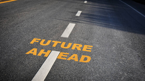 Future ahead word with white dividing lines on black asphalt road surface with sunlight, business challenge concept and effort idea