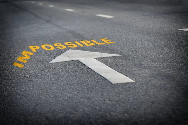 Impossible word without im with arrow on black asphalt road surface, business challenge concept and overcome success idea