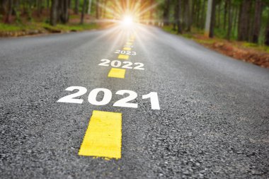 Yeni yıl yolculuğu 2021 'den 2024' e asfalt yol yüzeyinde işaretli çizgiler ve güneş ışığı ile. Ticari zorluk kavramı ve doğal arka plan fikri