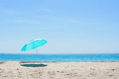 kumlu sahilde güneş şemsiyesi.