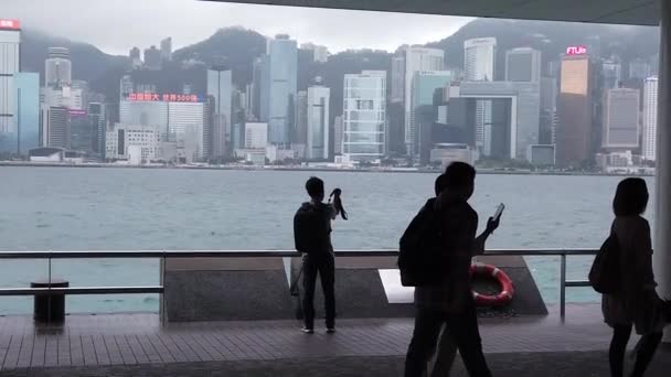 Hong Kong, China, 12 de abril de 2019: Slow Motion of Tourists visiting the waterfront in Tsim Sha Tsui at rain day- es un famoso destino turístico . — Vídeos de Stock