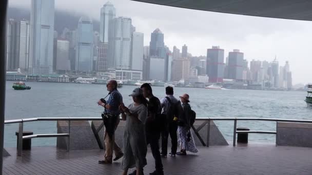 Hong Kong, Çin, 12 Nisan 2019: Yağmur gününde Tsim Sha Tsui'de sahili ziyaret eden turistlerin yavaş hareketi- ünlü turistik destinasyonlardan biridir. — Stok video