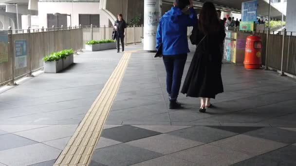 Les habitants asiatiques et les touristes traversant une passerelle piétonne à centra le jour de la pluie — Video