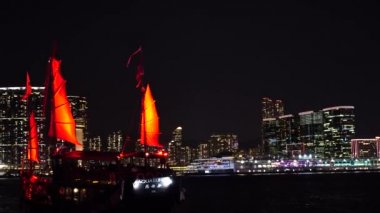 Hong Kong City gece görünümü kırmızı yelken önemsiz tekneler ile. 