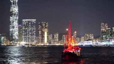 Hong Kong City gece görünümü kırmızı yelken önemsiz tekneler ile. 