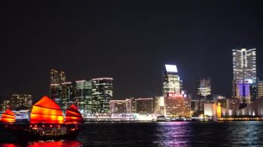 Hong Kong City gece görünümü kırmızı yelken önemsiz tekneler ile. 