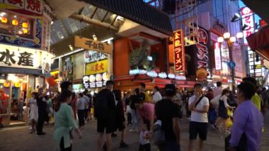 Osaka, Japonya, 17 Haziran 2019 : Gece Dotonbori'yi ziyaret eden turistlerin yavaş hareketi. Dotonbori, Japonya'nın Osaka bölgesinin en popüler seyahat sitesidir.