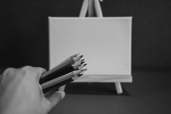 Hand with pencil on painting easel; Black and white style