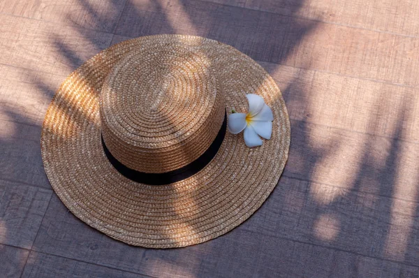 Flor exótica frangipani y sombrero sobre fondo de madera con sombra de palmeras el concepto de un Spa de ocio Imagen De Stock