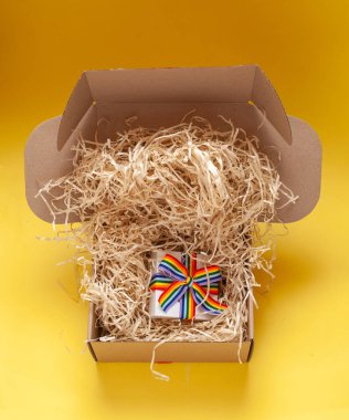Single white gift box with rainbow ribbon in open with recycled cardboard wiring and shipping box with fabric crimp top view filler clipart