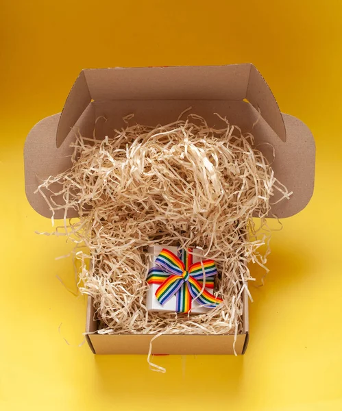 Caja de regalo blanca única con cinta de arco iris en abierto con cableado de cartón reciclado y caja de envío con relleno de vista superior engarzado de tela Fotos De Stock Sin Royalties Gratis