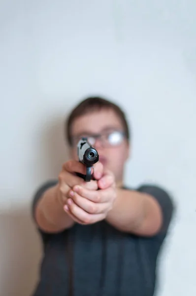 A 4,5 mm-es pisztoly veszélyes elülső szélének közeli közelről. Annak ellenére, hogy a mélységélesség rendkívül kicsi, a háttérben láthatjuk a homályos alakja egy tinédzser, aki egy pisztolyt. — Stock Fotó