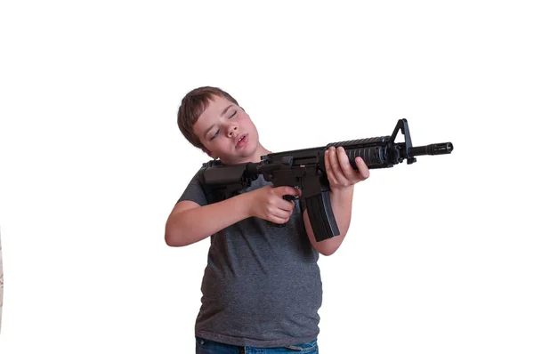 El niño sostiene una pistola de rifle y apunta hacia un lado. aislar Fotos De Stock