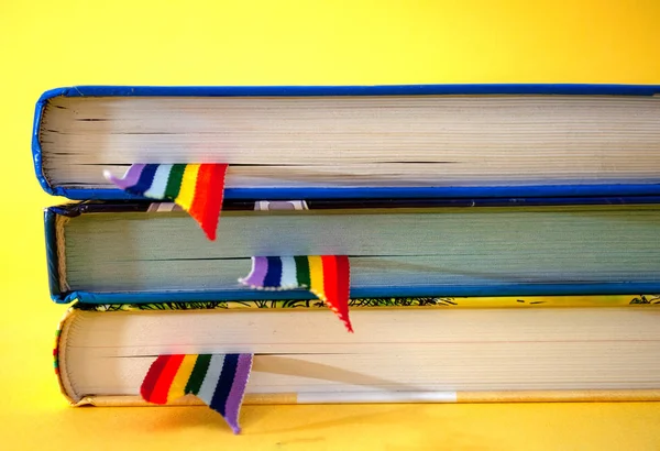 a stack of three books with rainbow ribbon bookmarks is on the table. Concept back to school, freedom, independence