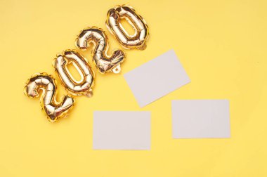 Sarı arka planda altın folyo topları. Şişme rakamlar 2020. Konsept yeni yıl, Noel. Alan üst görünümünü kopyalama
