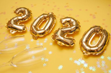 Sarı arka planda altın folyo topları. Şişme rakamlar 2020. Konsept yeni yıl, Noel. Alan üst görünümünü kopyalama