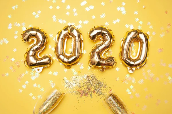 Bolas de lámina dorada sobre fondo amarillo. Cifras inflables 2020. Concepto año nuevo, Navidad. Copiar vista superior del espacio Imagen De Stock