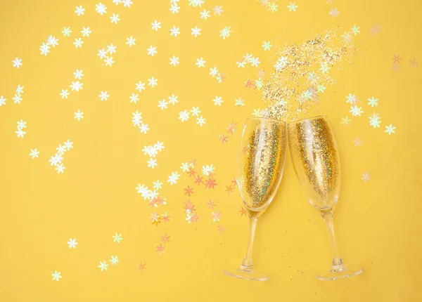 Copas de champán con confeti dorado, fondo amarillo brillo. celebración del año nuevo. Vista superior. El concepto de celebración . Fotos De Stock